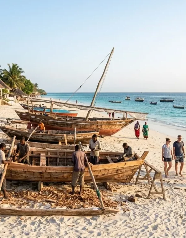 A dynamic horizontal documentary photograph capturing the unique energetic atmosphere of Nungwi beach, Northern tip of Zanzibar, during the breezy late afternoon golden hour. It features multiple local Swahili craftsmen building traditional large wooden dhow boats on the sand with hand tools, surrounding by construction materials and raw wood hulls. A lively social beach scene with local women in 'kangas', children playing, and international tourists observing unfolds nearby. Anchored weathered dhow boats are silhouetted against the rising sun out on the deep turquoise Indian Ocean. A rustic beach bar and palm-thatch structures are under mature coconut trees. Natural golden daylight illuminates the entire scene.